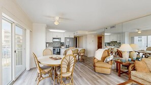 A spacious living area with a dining table, chairs, and a sofa. - Sand Pointe 102 (Ocean City)
