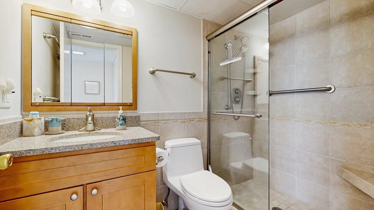 A bathroom with a toilet, a sink with a mirror, and a shower with a glass door.