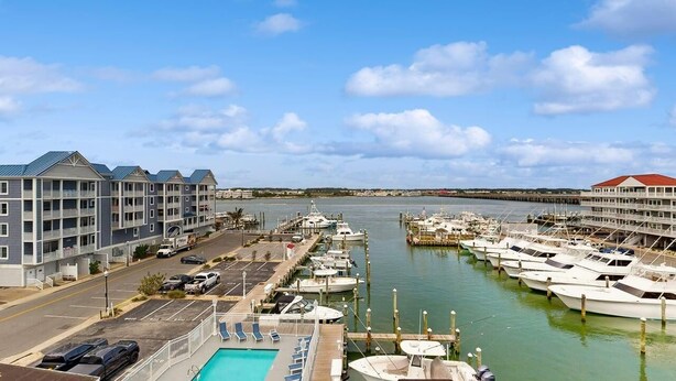 Puerto deportivo con barcos amarrados, piscina y hotel con balcones.
