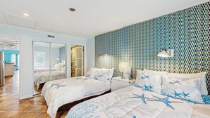 Un dormitorio con dos camas, un espejo, una mesita de noche y un papel tapiz estampado.
