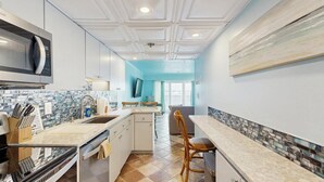 Una cocina moderna con microondas, pileta y espacio para sentarse en la barra.