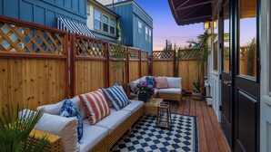 A covered outdoor seating area with a checkered floor, wooden fence, and a door. - Delridge ArtHaus - Spacious 4-bedroom house in beautiful Seattle with AC (Seattle)