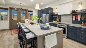 A modern kitchen with a central island, dark cabinetry, stainless steel appliances, and a view of the outdoors. - Delridge ArtHaus - Spacious 4-bedroom house in beautiful Seattle with AC (Seattle)