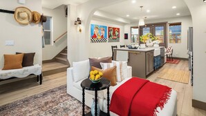 A modern living room with a sofa, a coffee table, and a red throw blanket. There is a staircase leading to another level. - Delridge ArtHaus - Spacious 4-bedroom house in beautiful Seattle with AC (Seattle)