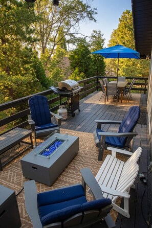 Terraza al aire libre con mobiliario, una parrilla y una chimenea.