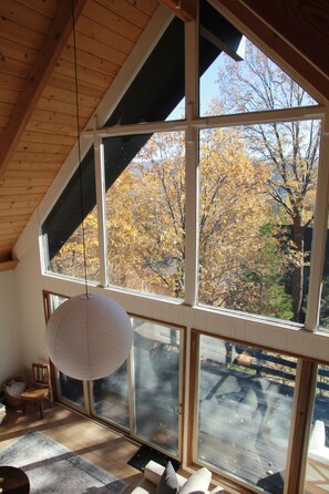 A room with large windows, a hanging light fixture, and a view of trees. - Baumhaus Lake Arrowhead - Family & Dog-Friendly Cabin w/ Game Room & Fenced Yard (Lake Arrowhead)