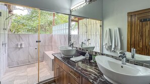 Ein modernes Badezimmer mit einem großen Spiegel, zwei Waschbecken und einer Duschkabine.