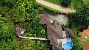 Eine Vogelperspektive eines Hauses mit Schwimmbad, umgeben von dichter Vegetation.