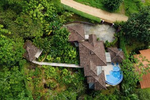 Eine Vogelperspektive eines Hauses mit Schwimmbad, umgeben von dichter Vegetation.