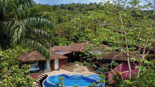 Ein tropisches Resort mit Schwimmbad, überdachter Terrasse und einem Gästezimmer mit Balkon.