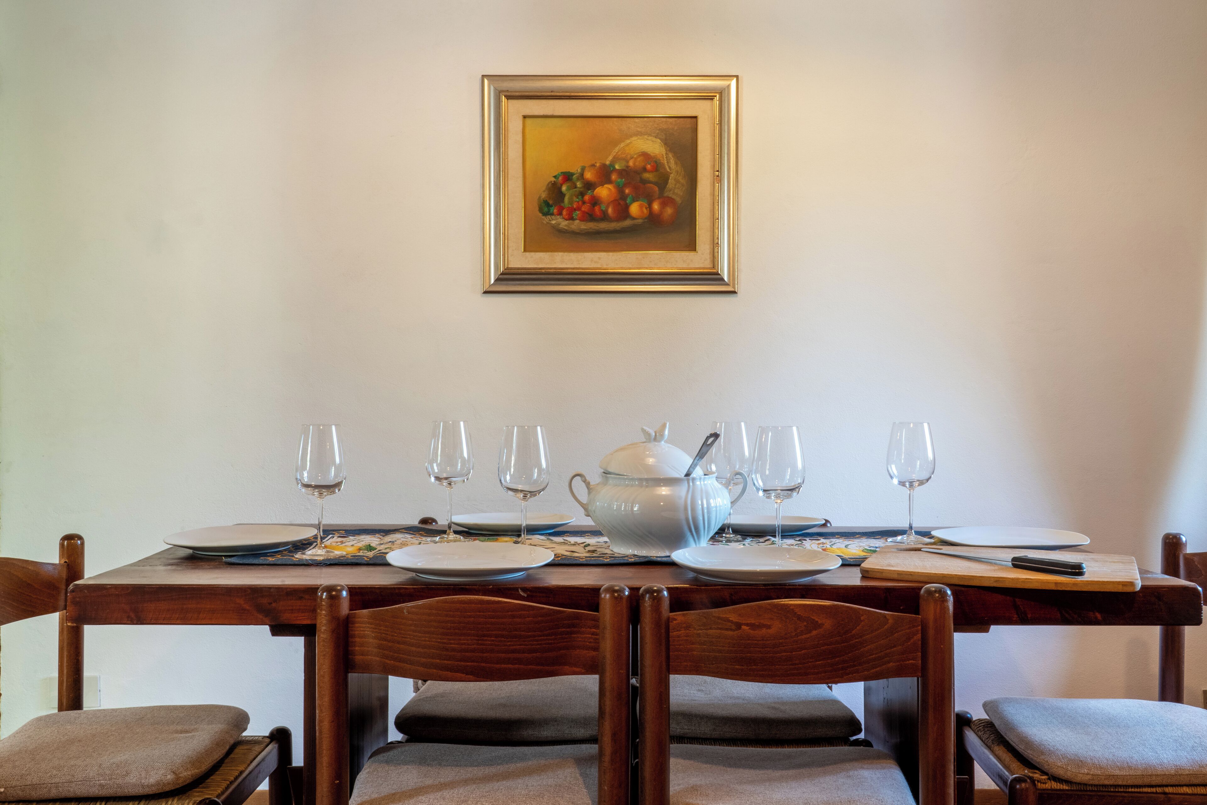 Een eettafel gedekt met borden, glazen en een theepot.
