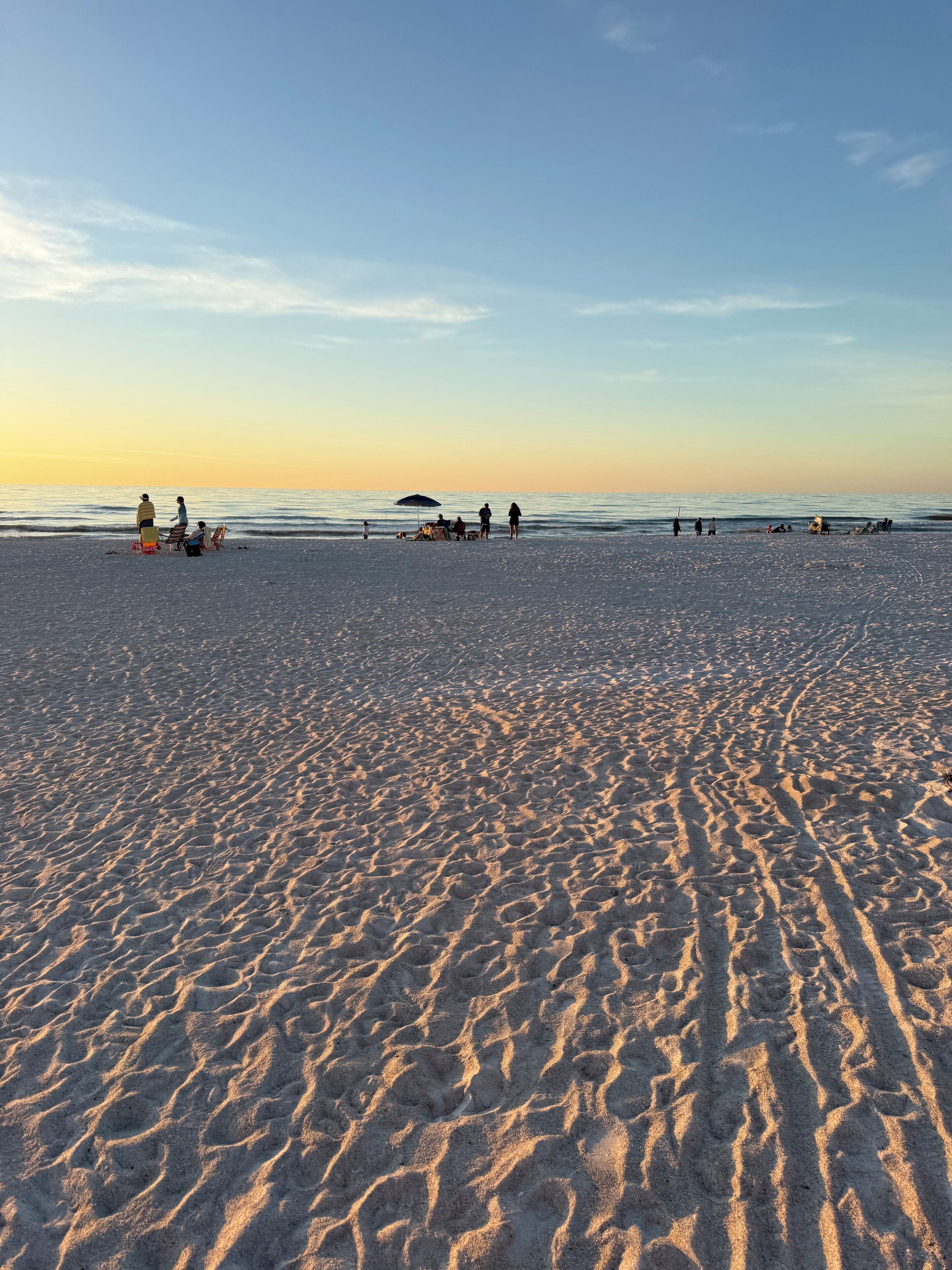 A beach with footprints in the sand and a clear sky.