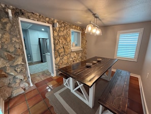 A dining area with a stone wall, a wooden table, and a bench.