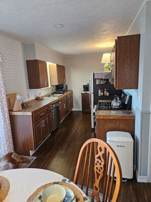 A compact kitchen with wooden cabinets, a microwave, a stove, and a refrigerator.