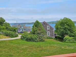 A coastal property with a grassy lawn, a wooden house, and a blue house with a red door. - Water Street Retreat (Eastport)