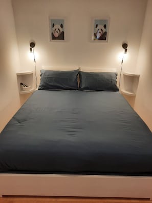A bed with a dark blue mattress, two pillows, and two bedside tables with lamps. - Domus Velia Central Apt | Just Steps from the Station, Port, and Old Town (Salerno)