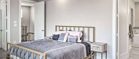 Une chambre à coucher comprenant un lit, une table de chevet et une porte donnant sur une salle de bain.