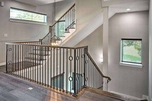 A staircase with a metal railing, a wooden floor, and a window with blinds. - 3-bedroom SFR in fabulous Houston with cool AC (Houston)