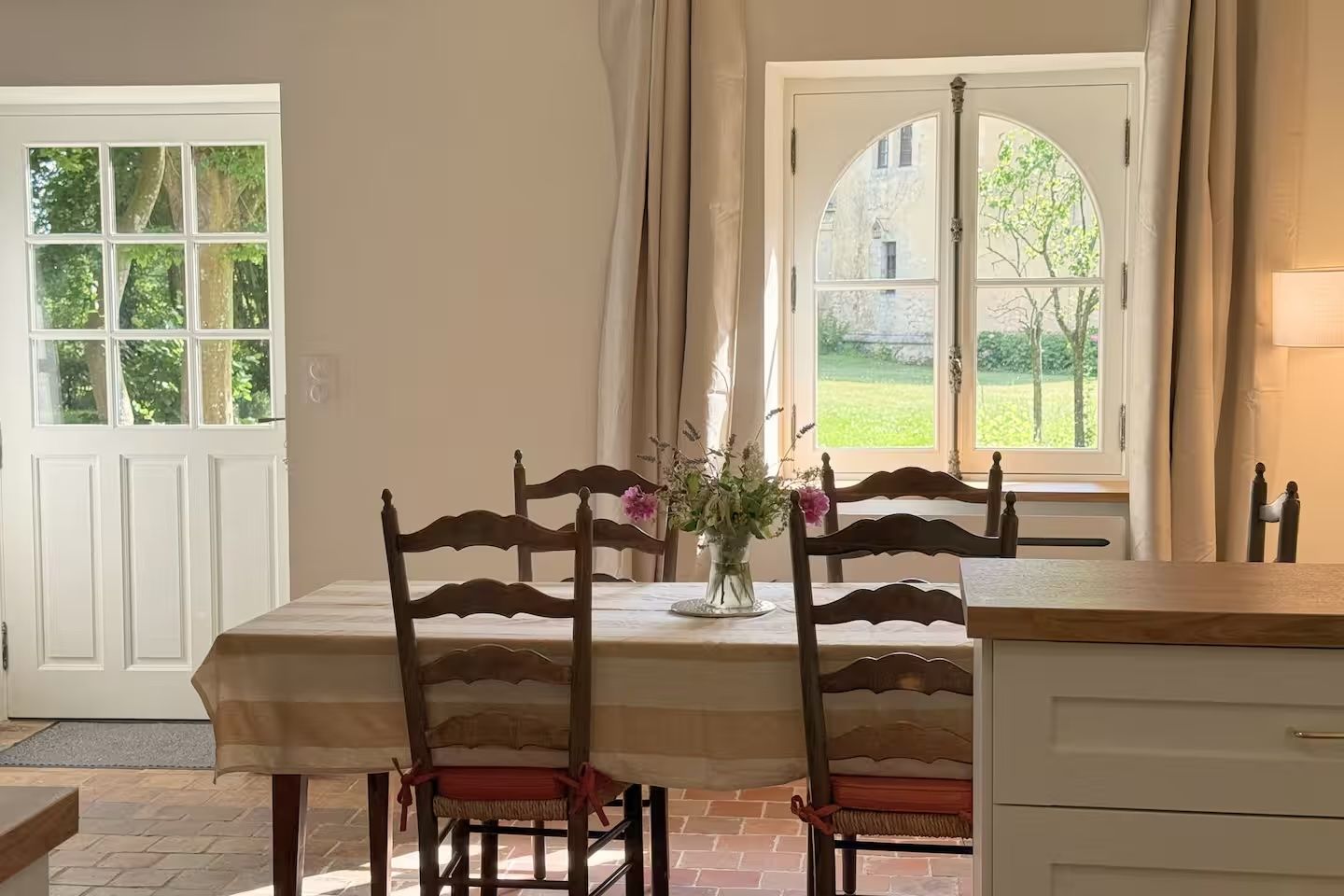 A dining area with a table, chairs, and a vase of flowers.