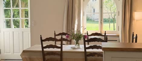 A dining area with a table, chairs, and a vase of flowers.