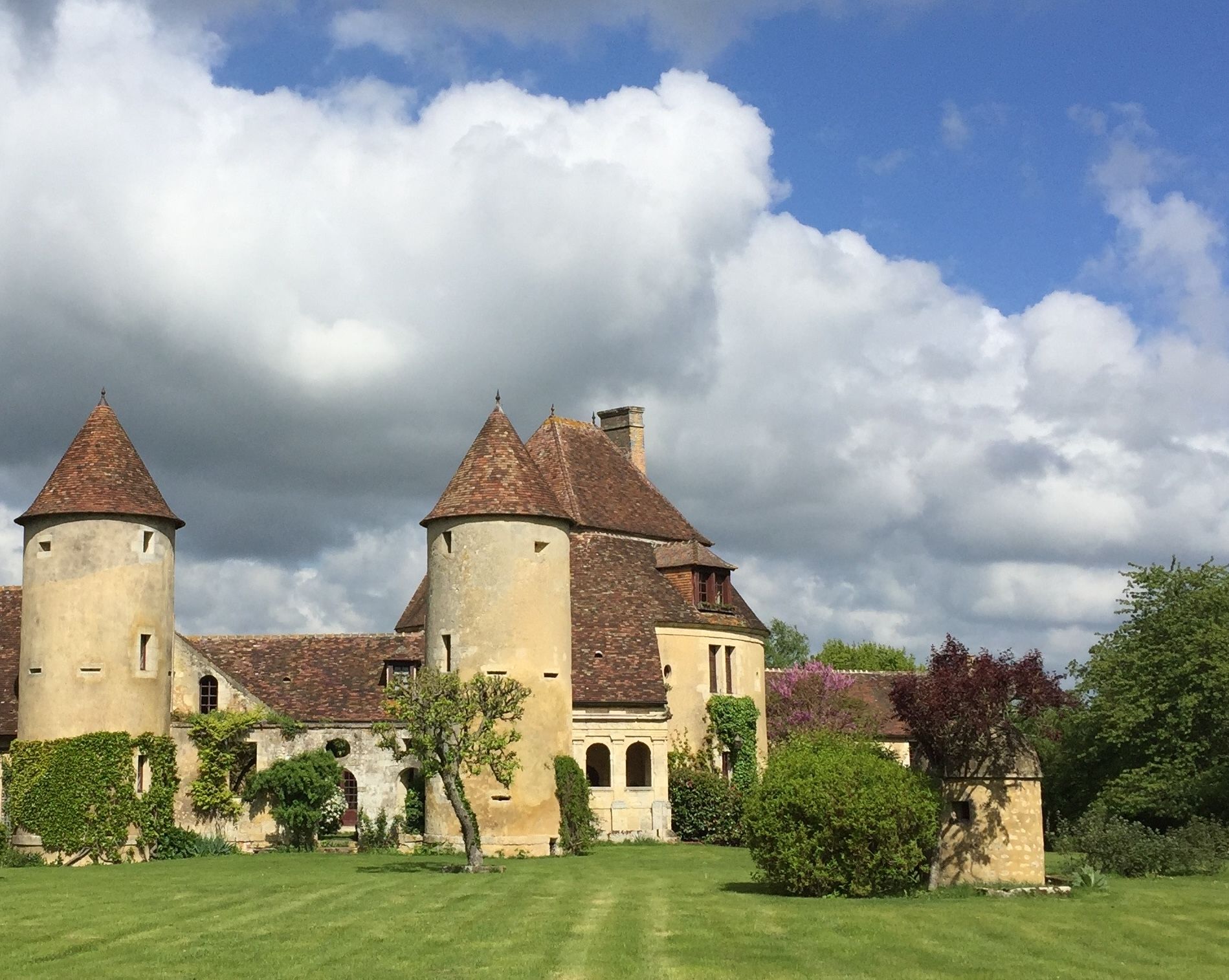 Un bâtiment historique doté de deux tours imposantes, d’une cour intérieure et entouré de verdure.