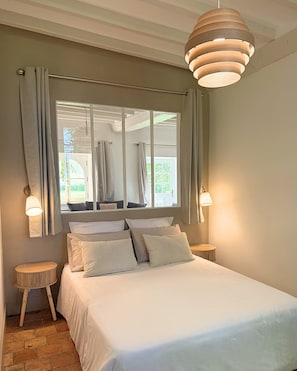A bedroom with a bed, two bedside tables, a hanging light fixture, and a window with curtains. - Les Bergeries across from a 16th-century manor house (Saint-Germain-de-la-Coudre)