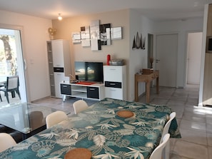 Ein modernes Wohnzimmer mit einem Glastisch, einem Flachbildfernseher und einem weißen Schrank.