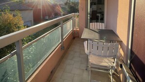A balcony with a table and chairs, a glass railing, and a view of the landscape. - GOLFE-JUAN (06220) WEEKLY STUDIO RENTAL – JULY & AUGUST (Vallauris)