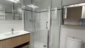 A modern bathroom with a glass-enclosed shower, a white sink, and a toilet. - GOLFE-JUAN (06220) WEEKLY STUDIO RENTAL – JULY & AUGUST (Vallauris)