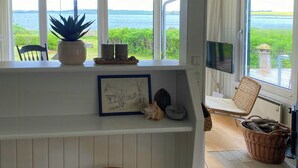 Eine Küche mit Meerblick, Holzschemeln, einem Blumentopf und einem gerahmten Bild.