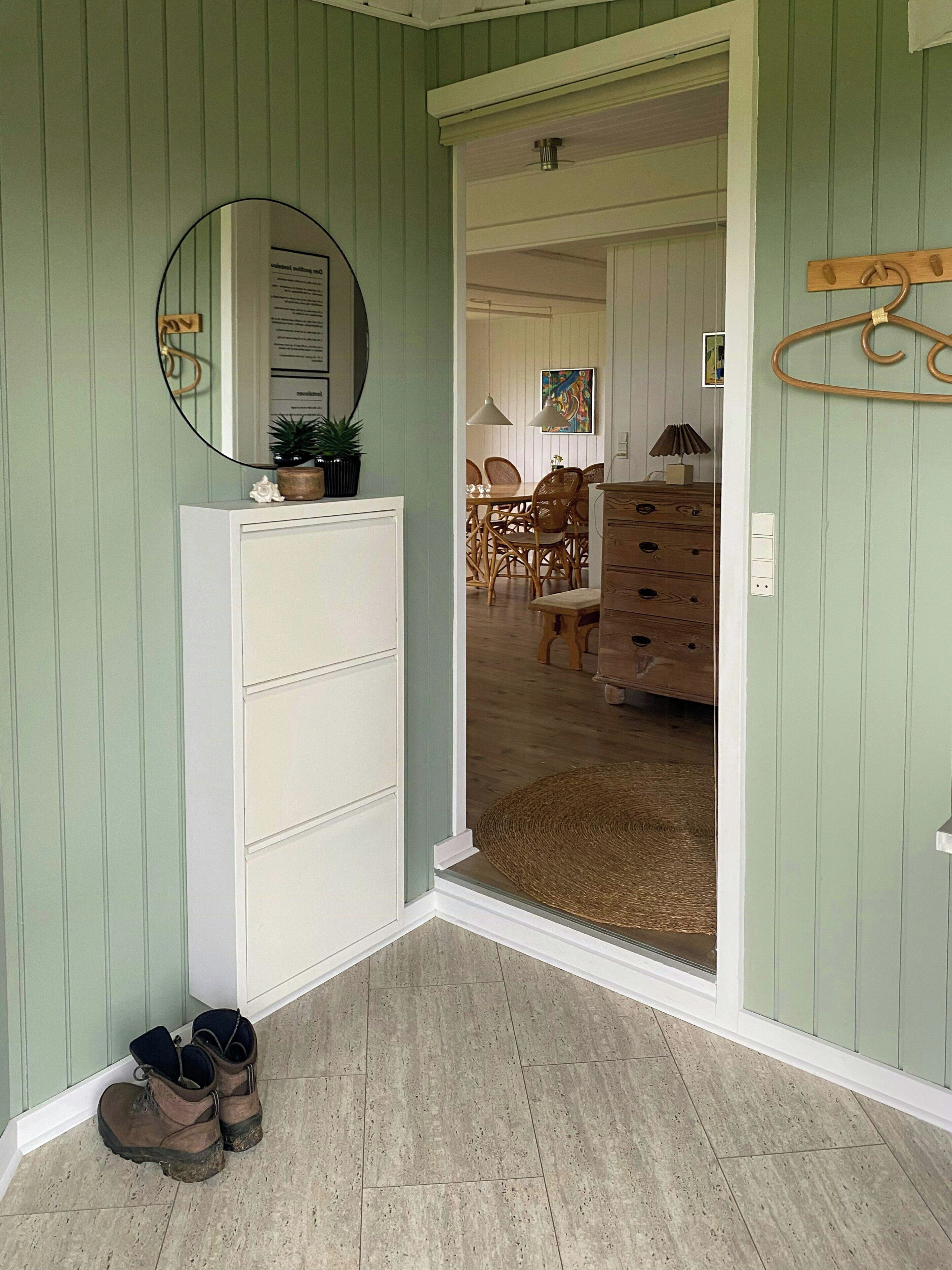 A room with a white dresser, a mirror, and a pair of boots on the floor.