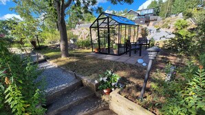 A garden with a gazebo, a small water feature, and a patio area with outdoor furniture.