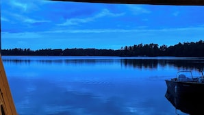 Un muelle de madera que conduce a un lago tranquilo con un bote amarrado a la derecha.