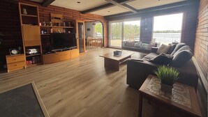Una sala de estar con televisor, estanterías de madera, un sofá y un balcón con vistas.
