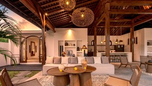 An outdoor living area with a sofa, two round tables, and wicker chairs. - Villa Amara in Kuta with 7 bedrooms and 7 bathrooms (Kuta)