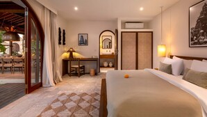 A hotel room with a bed, desk, chair, and a view of the outside. - Villa Amara in Kuta with 7 bedrooms and 7 bathrooms (Kuta)