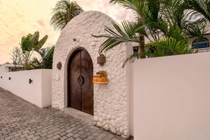 Un edificio con fachada de piedra, una puerta de madera grande y una cesta colgante pequeña.