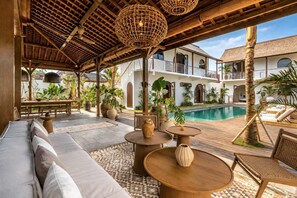 Un espacio de estar al aire libre cubierto, con una piscina al fondo.
