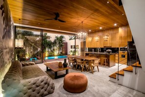 Eine moderne Küche mit Holzschnitzereien, eine Essecke mit Tisch und Stühlen, ein Sofa und eine Treppe.