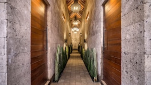 A corridor with a wooden floor, stone walls, and a chandelier. - Nusantara Loft Rote in Pererenan (Pererenan)