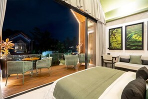 A modern hotel room with a balcony, a bed, a sofa, and a dining area with chairs and a table. - Sunset Lagoon Rice Field Villa (Ubud)