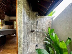 Ein Badezimmer mit Dusche, ein Bett und ein Fernseher im angrenzenden Raum.