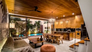 Una cocina moderna con armarios de madera, un comedor con mesa y sillas, un sofá y una escalera.