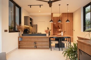 A modern kitchen with a central island, pendant lighting, and a staircase leading to an upper level. - Makia Loft in Canggu (Canggu)