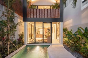 A modern building with a pool, glass doors, and lush greenery. - Makia Loft in Canggu (Canggu)