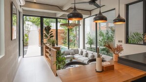 Ein offener Wohnbereich mit einem Holztisch, einer Couch und einem Deckenventilator.