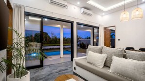 A modern living room with a sofa, a coffee table, and a view of a swimming pool. - Villa Grateful in Kecamatan Sukawati (Kecamatan Sukawati)