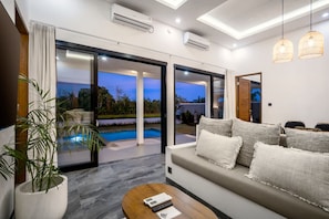 Ein modernes Wohnzimmer mit einer Couch, einem Couchtisch und Blick auf einen Swimmingpool.