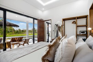 Une chambre moderne avec un grand lit, une tête de lit en bois, une vue sur l’extérieur et une étagère intégrée.