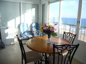 A dining area with a round table, chairs, a vase with flowers, and a view of the ocean through large windows. - Miramar Playa 6-2 in Benidorm (Benidorm)